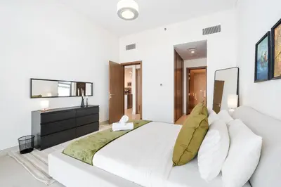 a white bedroom with a large bed and a television at Stunning 1BR Canal Front Residence near Downtown in Dubai