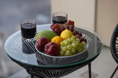 a bowl of fruit on a glass table with two glasses at Burj Khalifa & Fountain Balcony Views, Pool & Gym in Dubai