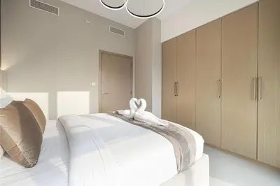 a bedroom with a bed with white sheets and wooden cabinets at Burj Khalifa & Fountain Balcony Views, Pool & Gym in Dubai