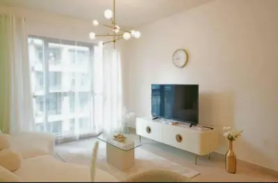 a living room with a tv and a white couch at Burj View 1BR Pool,Gym,Sauna,Dubai Mall in Dubai