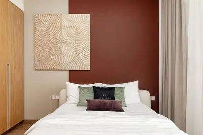 a bedroom with a white bed with a brown wall at Oakley Square 1BR Apartment with maid's room in Dubai