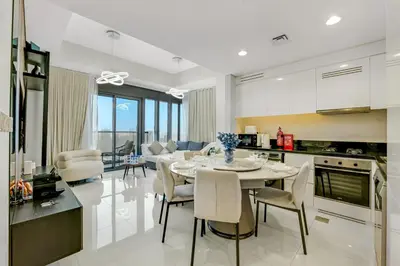 a kitchen and living room with a table and chairs at Guest Favorite - Premium 3BR with Skyline Views at Floor 50 in Dubai