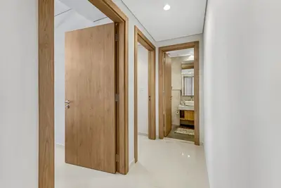 a hallway with a wooden door and a bathroom at Guest Favorite - Premium 3BR with Skyline Views at Floor 50 in Dubai