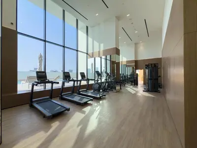 a gym with a row of treadmills and large windows at GuestReady - New Gem | JVC | Binghatti Gardenia in Dubai