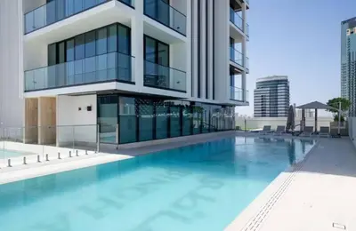 a building with a swimming pool in front of a building at Guest Favorite - Minimalist 1BR Escape with Balcony in the Heart of JVC in Dubai