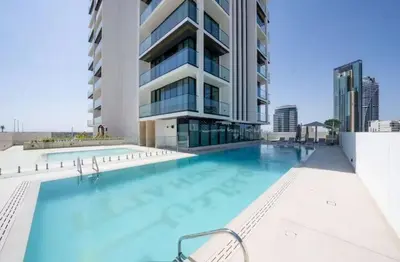 a large swimming pool in front of a building at Guest Favorite - Minimalist 1BR Escape with Balcony in the Heart of JVC in Dubai