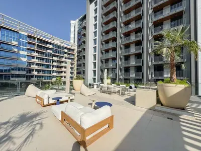 a patio with chairs and tables and buildings at Premium 2BR with Pool, Gym & Lifestyle Amenities in Dubai