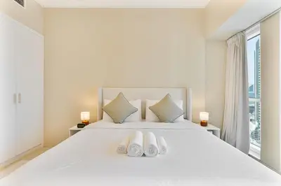 a bedroom with a white bed with two pairs of slippers at Upmarket - 1BR - Canal View - 9 MIN Dubai Mall in Dubai