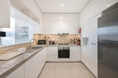 a kitchen with white cabinets and a stainless steel refrigerator at Golden Stays - Luxury 2BR I Burj Views & Direct Dubai Mall Access in Dubai