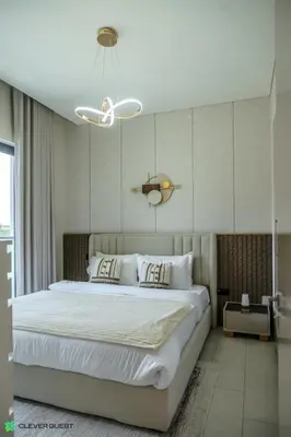 a bedroom with a large white bed with a chandelier at Clever Guest 032 Hartland Waves in Dubai