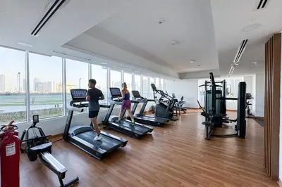 a group of people exercising on treadmills in a gym at Bright 1 Bedroom Apartment with JVC open view in Dubai
