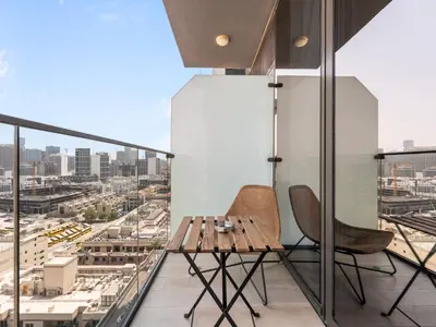 a balcony with a wooden table and two chairs at Bright 1 Bedroom Apartment with JVC open view in Dubai
