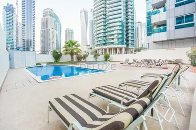 a group of lounge chairs sitting next to a swimming pool at Metro-Accessible 2BR, Easy Reach to Marina Mall and JBR Beach, Featuring Stunning SZR & City Views, Marina Diamond 2, Dubai Marina by Deluxe Holiday Homes in Dubai