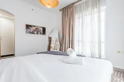 a white bedroom with a large bed and a window at Metro-Accessible 2BR, Easy Reach to Marina Mall and JBR Beach, Featuring Stunning SZR & City Views, Marina Diamond 2, Dubai Marina by Deluxe Holiday Homes in Dubai
