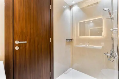 a bathroom with a shower and a wooden door at Sunny Studio with Pool, Near Silicon Central Mall in Dubai