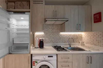 a kitchen with a washer and a sink and a refrigerator at Beachfront Studio at West Beach in Dubai