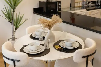 a white dining room table with two cups and chairs at Central 1BHK in JVC w Pool near Dubai Sports City in Dubai
