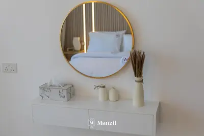 a mirror on a wall above a white shelf with a bed at Central 1BHK in JVC w Pool near Dubai Sports City in Dubai
