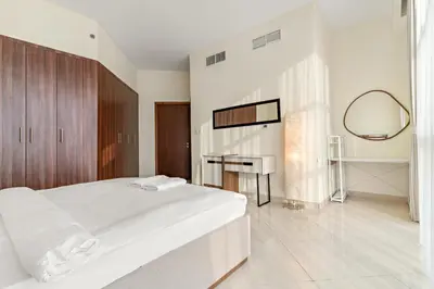 a white bedroom with a large bed and a mirror at FIRST CLASS 1BR Stylish Vibe in Dubai