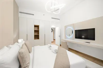 a white bedroom with a large bed and a flat screen tv at Luxury La Mer 1BR Balcony Sea Views Near City Walk and Mall in Dubai