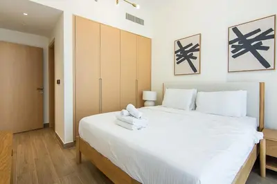 a bedroom with a large white bed with towels on it at Brand New 1 Bedroom in AURA by Grovy, JVC in Dubai