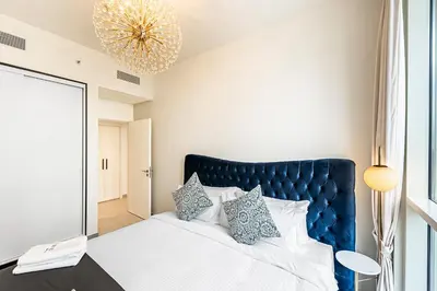 a bedroom with a bed with a blue headboard and a mirror at Escape 24 Lux 2BR Collective Dubai Hills in Dubai