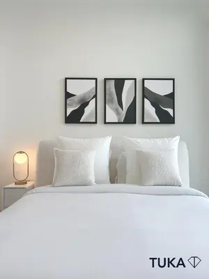 a white bedroom with a white bed with four pictures on the wall at Canal View - 2-BHK - Creek Harbour - Central - Lux in Dubai