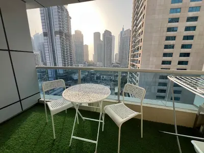 a table and chairs on a balcony with a view of a city at Italian-Style 2BR - Near Beach, Metro and Mall in Dubai