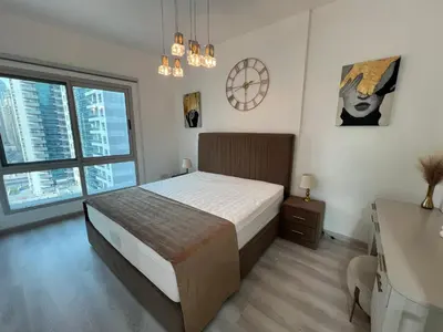 a bedroom with a bed and a desk and windows at Italian-Style 2BR - Near Beach, Metro and Mall in Dubai