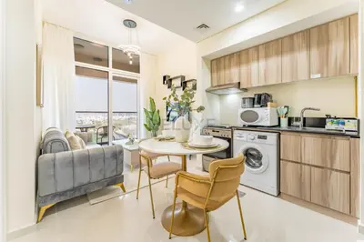 a kitchen and living room with a table and chairs at Conveniently Located Minutes from Dubai Hills Mall, Park, Golf Club, and Essential City Landmarks 1BR with Premium Facilities, Damac Hills Golf Vita A, Damac Hills 1 by Deluxe Holiday Homes in Dubai