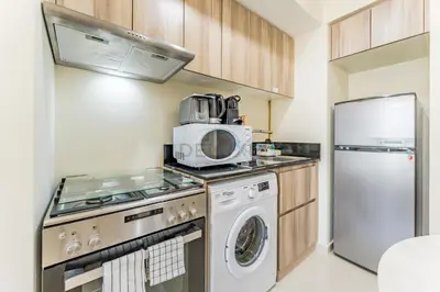 a kitchen with a washing machine and a microwave at Conveniently Located Minutes from Dubai Hills Mall, Park, Golf Club, and Essential City Landmarks 1BR with Premium Facilities, Damac Hills Golf Vita A, Damac Hills 1 by Deluxe Holiday Homes in Dubai
