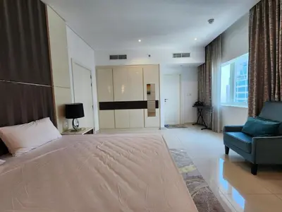 a bedroom with a large bed and a chair at Stylish Suites 1 Br Business Bay in Dubai