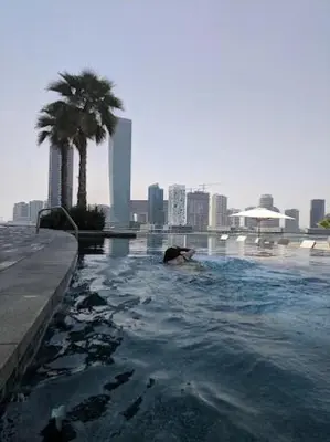 a person swimming in a swimming pool in a city at Stylish Suites 1 Br Business Bay in Dubai