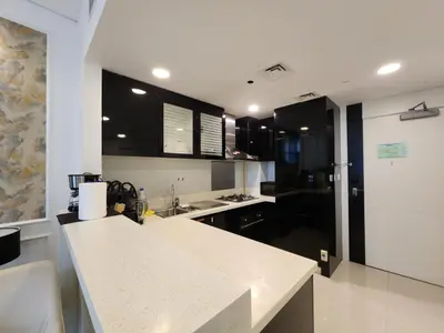 a kitchen with black cabinets and a white counter top at Stylish Suites 1 Br Business Bay in Dubai