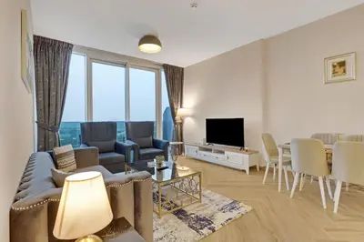a living room with a couch and a tv and chairs at 1 Residences High-Floor Apt with City View, Al Kifaf in Dubai