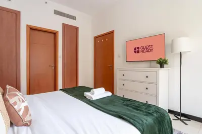 a bedroom with a bed with a green blanket on it at GuestReady - Furnished 1BR+Sofa | Al Alka Greens in Dubai