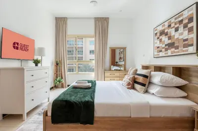 a bedroom with a large bed and a large window at GuestReady - Furnished 1BR+Sofa | Al Alka Greens in Dubai