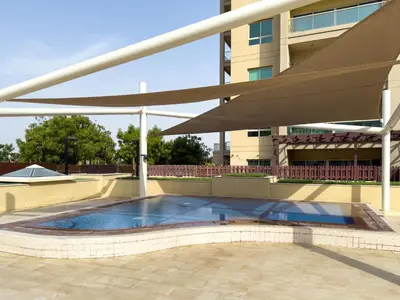 a swimming pool in front of a building at GuestReady - Furnished 1BR+Sofa | Al Alka Greens in Dubai
