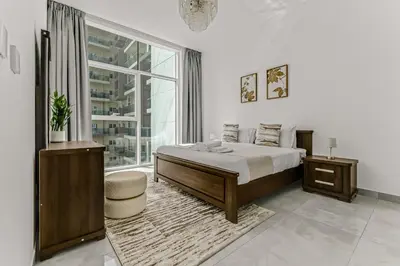 a bedroom with a bed and a large window at stylish 1BR Pearlz Pool & Gym Near Metro in Dubai