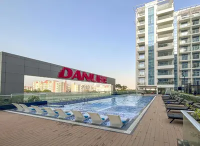 a swimming pool with lounge chairs in front of a building at stylish 1BR Pearlz Pool & Gym Near Metro in Dubai