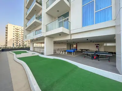 an apartment building with a green lawn in front of a building at stylish 1BR Pearlz Pool & Gym Near Metro in Dubai