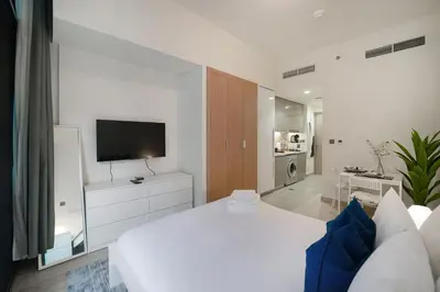 a white bedroom with a large bed and a television at EasyGo- Spacious, Low Floor and Pool view STU in Dubai