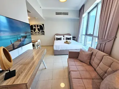 a living room with a couch and a bed at Opposite JBR Beach - Modern Studio in Dubai