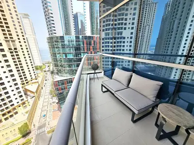 a balcony with a couch and a table and some buildings at Opposite JBR Beach - Modern Studio in Dubai