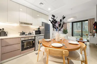 a kitchen and dining room with a wooden table and chairs at Stylish 1BR with Netflix Pool & Gym Access in Dubai
