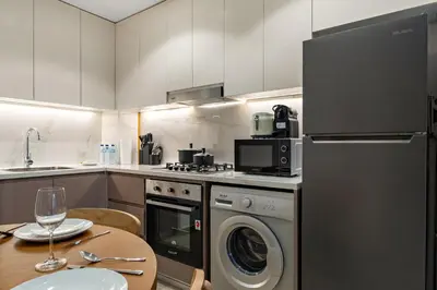 a kitchen with a washer and dryer and a table at Stylish 1BR with Netflix Pool & Gym Access in Dubai