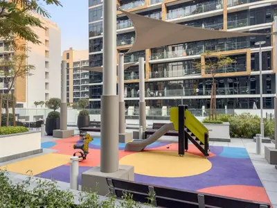 a playground with a slide in front of a building at Stylish 1BR with Netflix Pool & Gym Access in Dubai