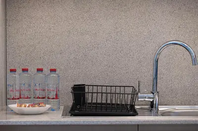 a kitchen sink with a basket next to a faucet and water bottles at Burj Royale Luxury 2BR Burj Khalifa & Fountain View 5 Min Walk Dubai Mall, 500MBPS Wifi in Dubai