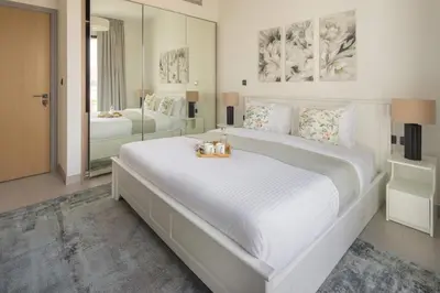 a white bedroom with a large bed with a mirror at Frank Porter - Hyati Avenue in Dubai