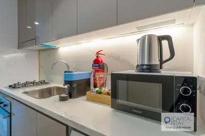 a kitchen counter with a microwave and a sink at Cozy Apartments in Azizi Riviera Dubai in Dubai